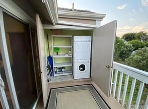 Enjoy fresh air and a convenient laundry station on this balcony with a door leading to the interior.