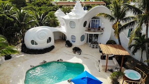 Un resort con un edificio blanco distintivo, una piscina y asientos al aire libre.