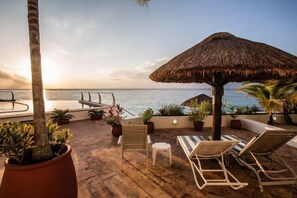 A wooden deck with lounge chairs and a thatched umbrella, overlooking a calm sea. - Spectacular 5th Floor Condo, Close to Town, Best Sunsets in Cozumel (Cozumel)