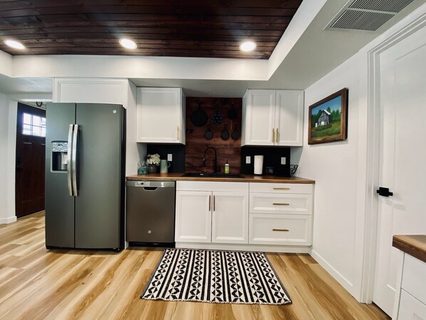 A modern kitchen with white cabinets, a stainless steel refrigerator, and a wooden countertop. - Beautifully updated cottage right in the heart of Fertile, Iowa! (Fertile)