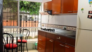 Una cocina con refrigerador, estufa y comedor con sillas.