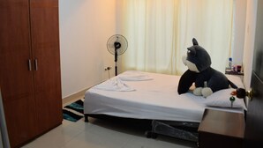 Un dormitorio con cama, ventilador, armario y ventana con cortinas.