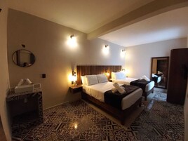 Quarto de hotel com uma cama grande, duas mesinhas de cabeceira, um espelho e carpete estampado.