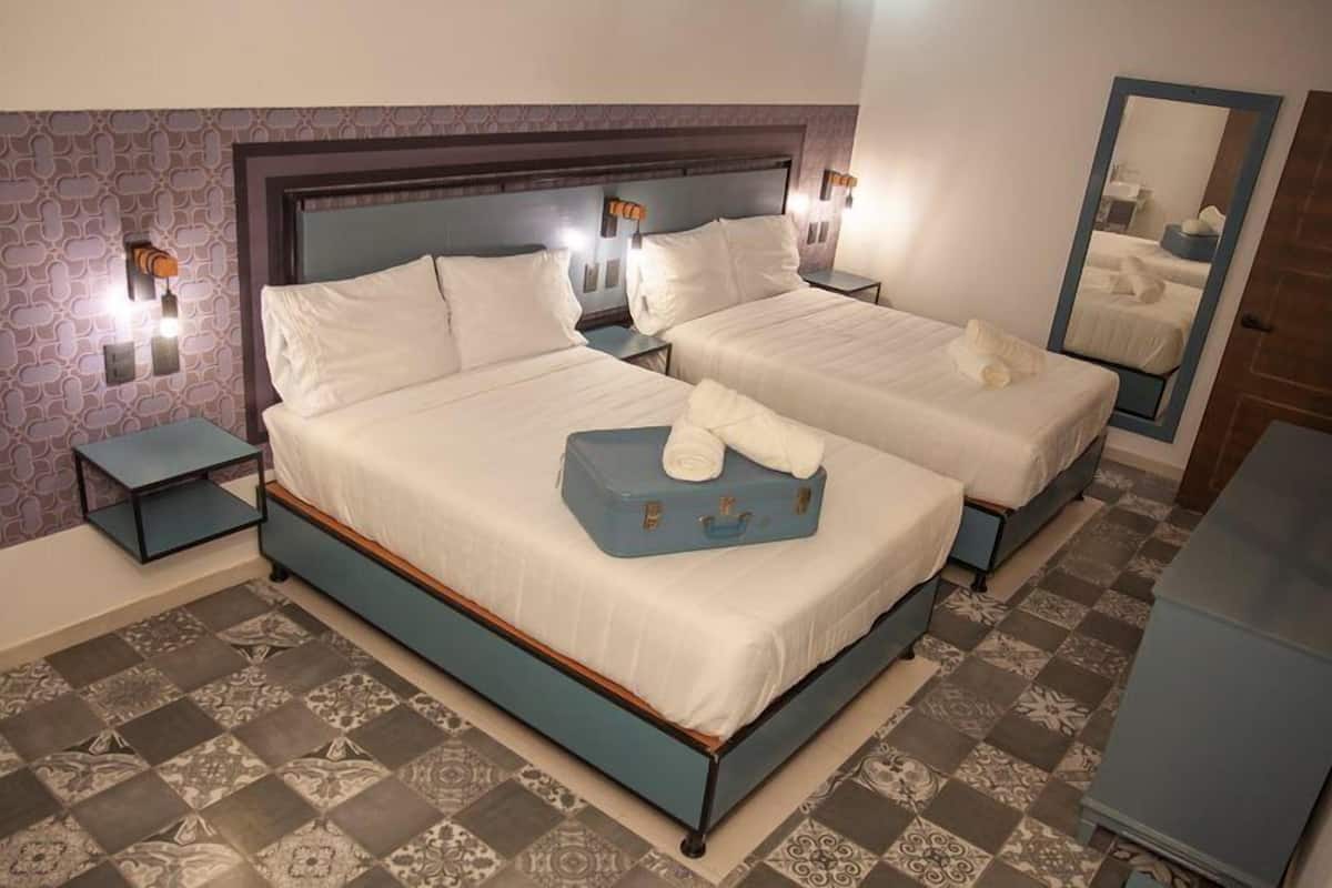 A hotel room with two beds, a large mirror, and a dresser.
