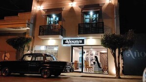 Um hotel com fachada clássica, um carro preto estacionado em frente e uma placa com o nome 'Anotanza'.