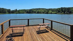 Une terrasse en bois avec des tables de pique-nique et une rambarde donnant sur un lac.