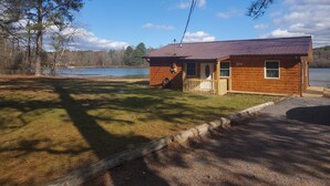 Une cabane en bois avec un porche, située près d’un lac.