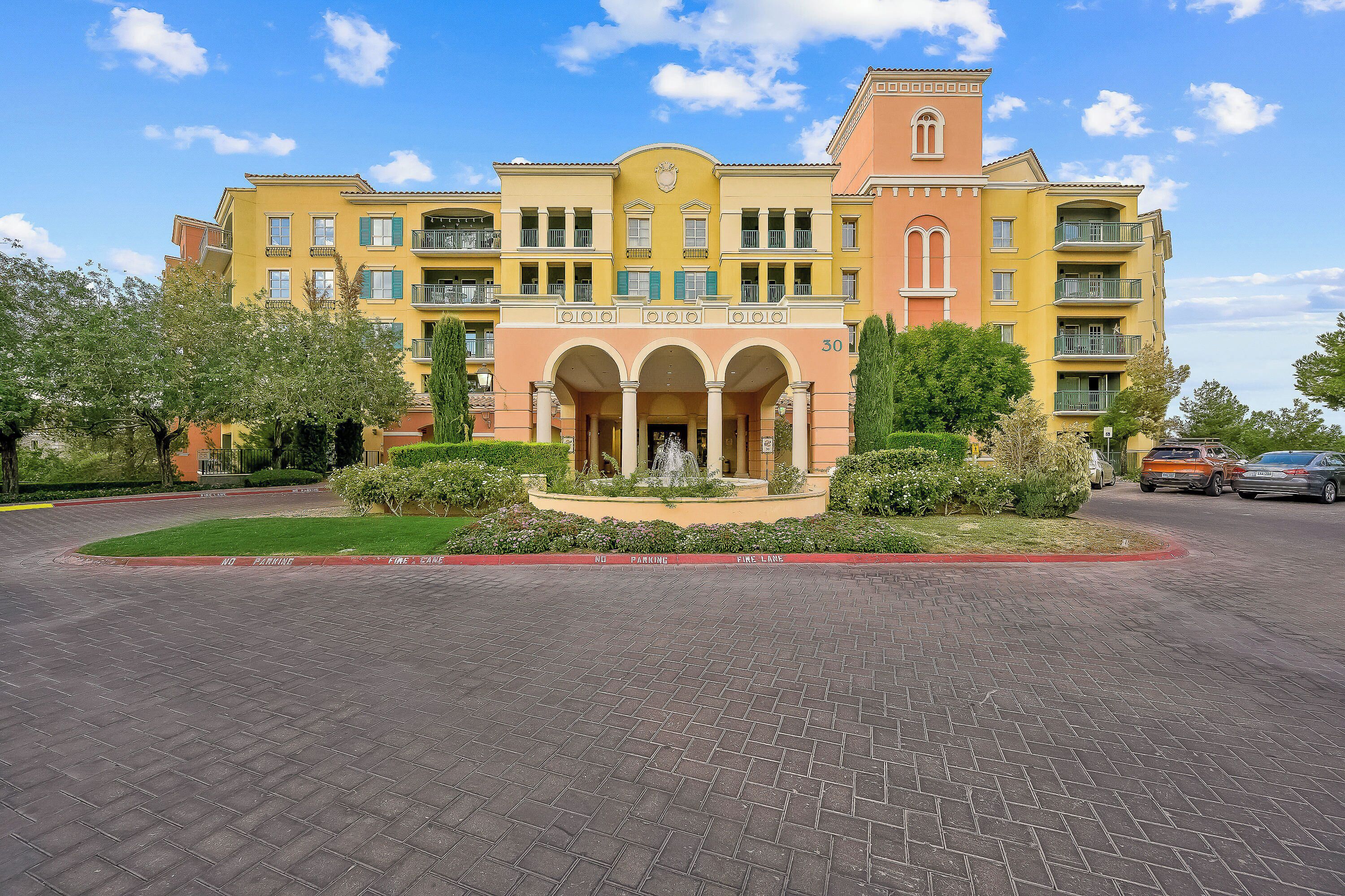 Un hotel de varios pisos con un patio central, balcones y una fuente.