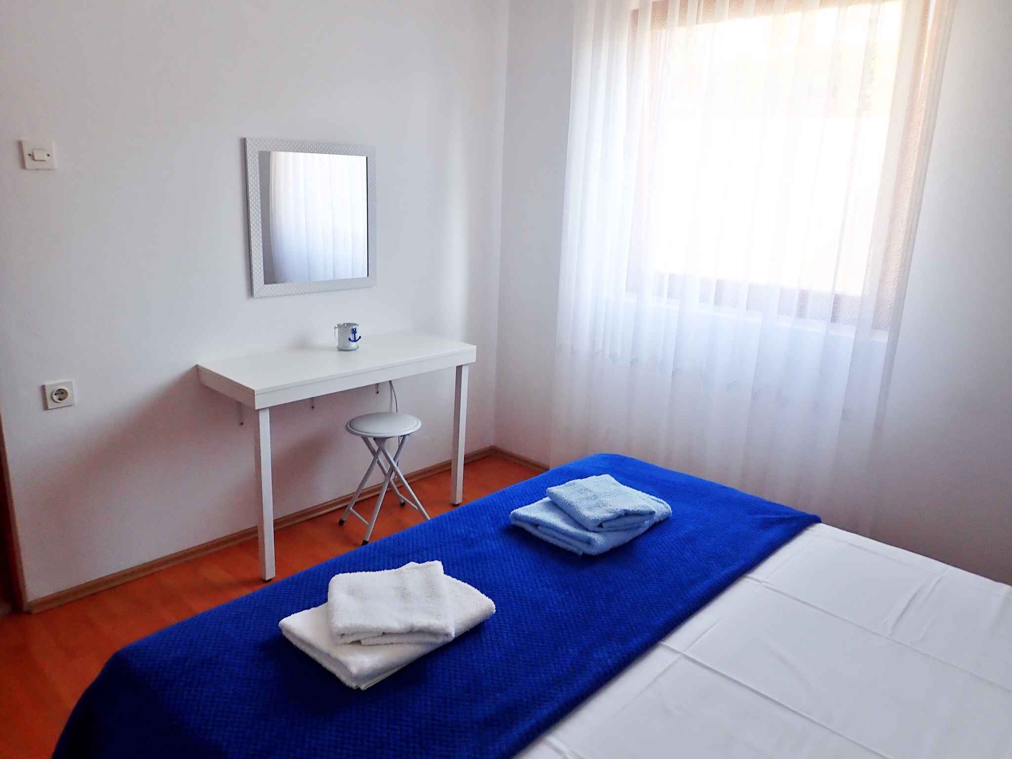 Una habitación de hotel con cama, escritorio, silla, espejo y ventana con cortinas.