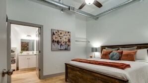 Ein Schlafzimmer mit einem hölzernen Bett, einem Nachttisch, einer Wandlampe und einem Blumenbild.
