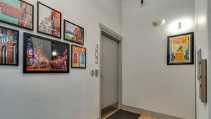 A hallway with framed pictures on the walls, a door labeled "302", and a wooden floor. - Majestic Lofts #302- Balcony over Printers Alley (Nashville)