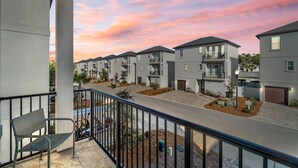 A residential area with modern houses, a balcony with a chair, and a clear sky.