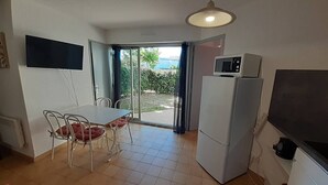 A compact kitchen with a dining area, a refrigerator, a microwave, and a TV. - Nice 2 room apt with Pool Richelieu beach Cap d'Agde (LE CAP D AGDE)