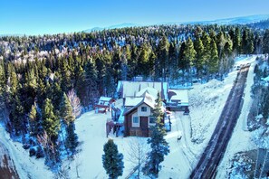 En stuga med träfasad, en veranda och ett snötäckt landskap.