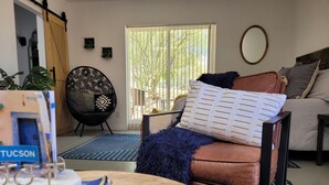 Ein Wohnzimmer mit braunem Ledersofa, einem schwarzen Sessel, einem Holztisch und einem Fenster mit Jalousien.