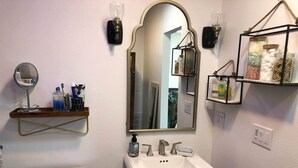 Ein Badezimmer mit Waschbecken, Spiegel, Toilette und Ablage für Pflegeprodukte.