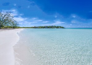 Une plage à l’eau turquoise et limpide, bordée d’un rivage sablonneux.