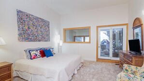 A bedroom with a large bed, a dresser, a television, a window, and a door leading to a balcony. - Cimarron Slopeside Retreat  Ski In/Ski Out (Telluride)