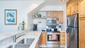 A modern kitchen with wooden cabinets, stainless steel appliances, and a marble countertop. - Cimarron Slopeside Retreat  Ski In/Ski Out (Telluride)