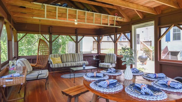 A covered outdoor seating area with wooden furniture, a table set with blue napkins, and a ladder on the ceiling. - Private Downtown Wellfleet Location! (Wellfleet)