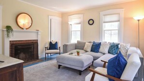 A living room with a fireplace, a sectional sofa, a coffee table, and a floor lamp. - Private Downtown Wellfleet Location! (Wellfleet)