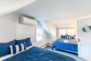 A bedroom with two beds, a white door, and a life ring on the wall.