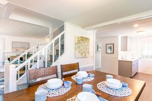 A dining area with a wooden table set for four, white plates, and blue napkins.