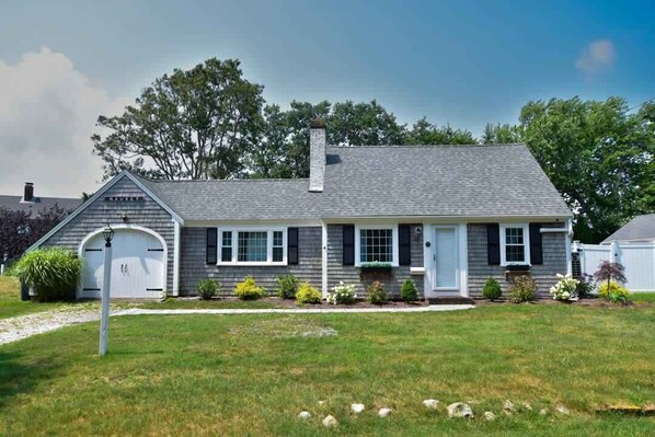 A two-story house with a garage, a front porch, and a well-maintained lawn.