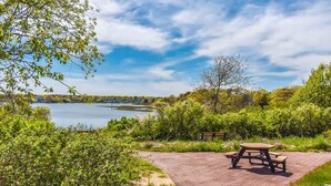 Un espace pique-nique équipé d’une table et de bancs, entouré de verdure et offrant une vue sur un lac.