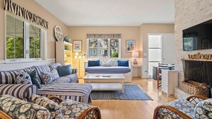 A cozy living room with striped sofas, a central coffee table, and a fireplace. - Updated Beach House Deck Outdoor Shower! (Chatham)