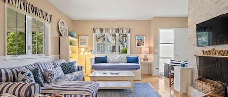 A cozy living room with striped sofas, a central coffee table, and a fireplace.