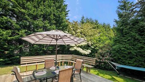 A wooden deck with a glass table, chairs, and a striped umbrella. - Updated Beach House Deck Outdoor Shower! (Chatham)