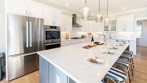 Una cucina moderna con elettrodomestici in acciaio inossidabile, un'isola in marmo e lampade a sospensione.
