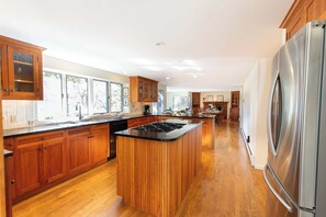 A modern kitchen with wooden cabinets, a central island, and a stainless steel refrigerator. - Steps to Skaket Beach! (Orleans)
