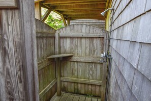 A wooden outdoor shower stall with a metal faucet and a shelf. - Steps to Skaket Beach! (Orleans)