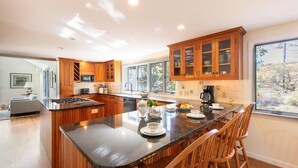 Une cuisine moderne avec des meubles en bois, un grand îlot central et un coin repas avec des chaises.