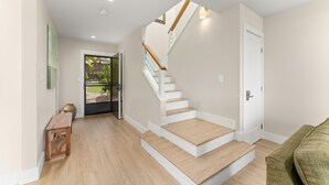 A modern interior with a staircase, wooden flooring, and a green sofa. - Beautifully remodeled ocean view condo in Wailea WE27B (Kihei)