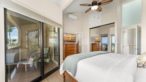 A bedroom with a large bed, a ceiling fan, a wooden dresser, and a sliding glass door leading to a balcony. - Beautifully remodeled ocean view condo in Wailea WE27B (Kihei)