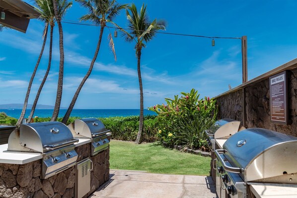 Enjoy al fresco dining with a barbecue setup featuring two grills, overlooking the ocean and lush surroundings.