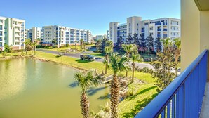 A residential area with modern apartment buildings, a small pond, and palm trees. - Oceanwalk 2BR | Fountain Views, Private Balcony & 5-Min Walk to Beach (New Smyrna Beach)