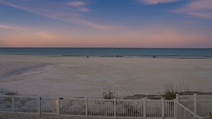 A beach with a white fence in the foreground.