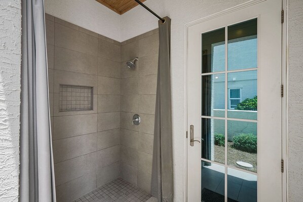 A walk-in shower with a glass door, tiled walls, and a small window. - Arena Blanca - Gulf View Home in Private, Gated Community of Vizcaya on 30A! (Santa Rosa Beach)
