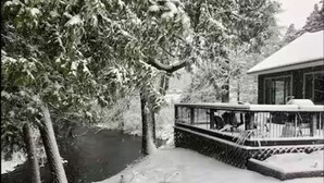 Une terrasse enneigée, dotée d’une balustrade, qui offre une vue sur une rivière.