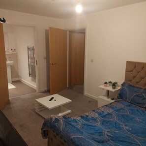 A bedroom with a bed, bedside table, and a small bedside plant.