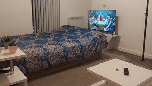 Un dormitorio con cama, televisión, escritorio y silla.