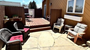 Un espace extérieur aménagé avec un sol en pierre, des meubles en osier et une terrasse en bois.