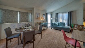 Un salon avec un canapé, une table à manger avec des chaises et un coin cuisine avec une fenêtre.