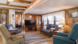 Una sala de estar acogedora con un sofá, sillones, un televisor y paredes de madera.