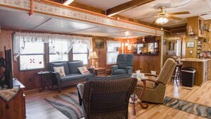 Un acogedor interior de cabaña con una sala de estar que incluye un sofá, sillas y una mesa de comedor.