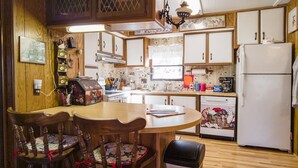 Una cocina con armarios de madera, un refrigerador, un lavamanos y una mesa de comedor con sillas.